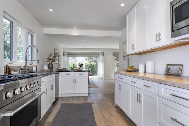 510 Miramonte Dr, Santa Barbara, CA 93109 - kitchen with appliances with stainless steel finishes, wood finished floors, white cabinetry, recessed lighting, and a sink