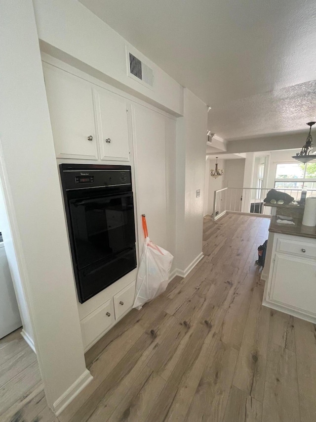 4305 Redwood Ave Unit 10, Los Angeles, CA 90292 - kitchen with black oven, light wood-type flooring, white cabinets, a textured ceiling, and a chandelier