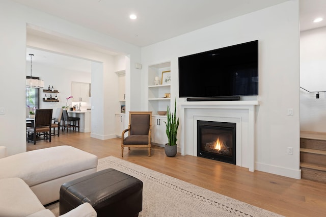 3736 State St Unit 109, Santa Barbara, CA 93105 - living room with built in shelves, wood finished floors, a glass covered fireplace, recessed lighting, and baseboards
