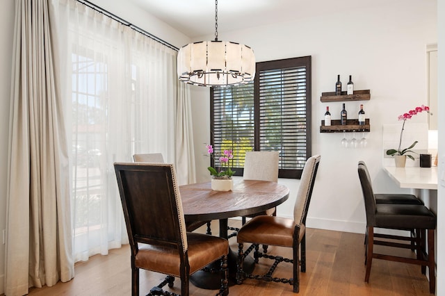 3736 State St Unit 109, Santa Barbara, CA 93105 - dining space with a chandelier, wood finished floors, baseboards, and bar area