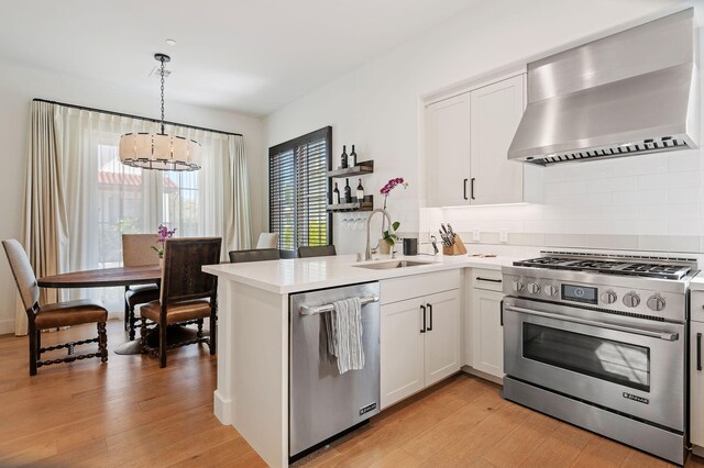 3736 State St Unit 109, Santa Barbara, CA 93105 - kitchen featuring stainless steel appliances, a sink, wall chimney range hood, a chandelier, and light wood-style flooring