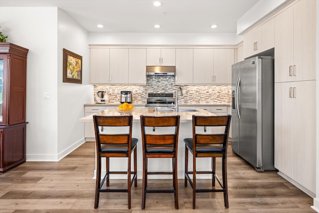 5696 Surfrider Way Unit 101, Goleta, CA 93117 - kitchen with appliances with stainless steel finishes, under cabinet range hood, a sink, light wood-style flooring, and recessed lighting