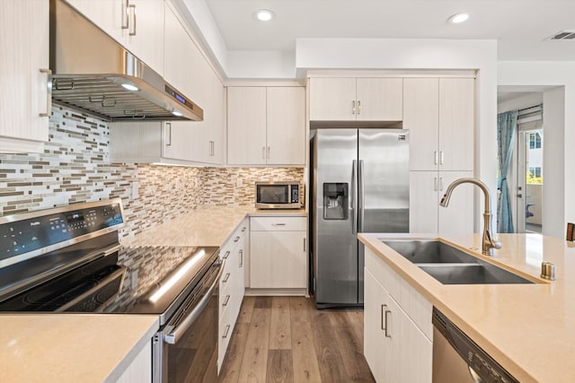 5696 Surfrider Way Unit 101, Goleta, CA 93117 - kitchen with stainless steel appliances, a sink, under cabinet range hood, light countertops, and wood finished floors