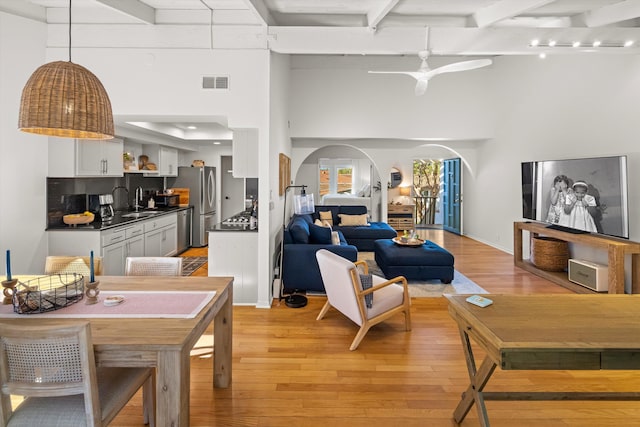 2648 State St Unit 32, Santa Barbara, CA 93105 - living room featuring arched walkways, light wood-style flooring, beamed ceiling, a ceiling fan, and a high ceiling