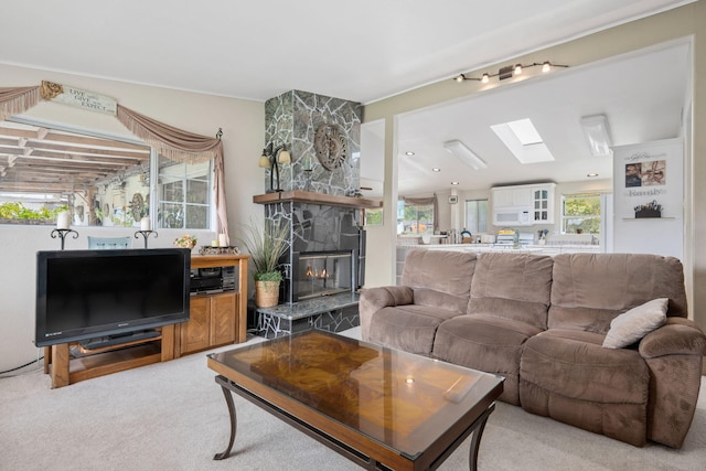 5671 Cathedral Oaks Rd, Goleta, CA 93117 - living area featuring a stone fireplace, healthy amount of natural light, a skylight, and light carpet