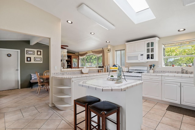 5671 Cathedral Oaks Rd, Goleta, CA 93117 - kitchen with white appliances, tile counters, light tile patterned floors, open shelves, and a skylight