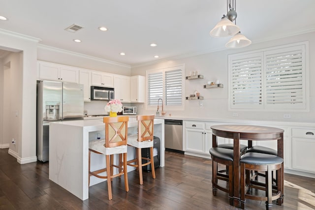 4538 Marrisa Way, Camarillo, CA 93012 - kitchen featuring appliances with stainless steel finishes, ornamental molding, a center island, a kitchen breakfast bar, and white cabinetry