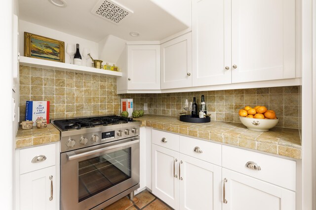 924 Garden St Unit F, Santa Barbara, CA 93101 - kitchen with stainless steel range with gas stovetop, open shelves, white cabinetry, tasteful backsplash, and tile counters