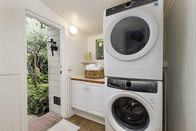 924 Garden St Unit F, Santa Barbara, CA 93101 - laundry area with stacked washer and clothes dryer, cabinet space, carpet, and healthy amount of natural light