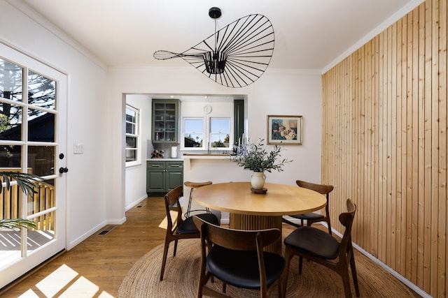 355 Palisades Dr, Santa Barbara, CA 93109 - dining space featuring wood finished floors, crown molding, wooden walls, baseboards, and a chandelier