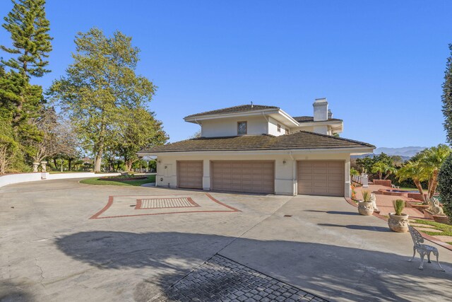 5287 N Creston Ln, Somis, CA 93066 - view of home's exterior featuring driveway, a chimney, stucco siding, a garage, and a tile roof
