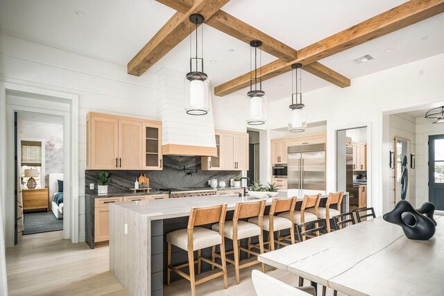 123 Polo Way, Santa Barbara, CA 93013 - kitchen with stainless steel built in refrigerator, backsplash, beam ceiling, a kitchen breakfast bar, and light wood-type flooring