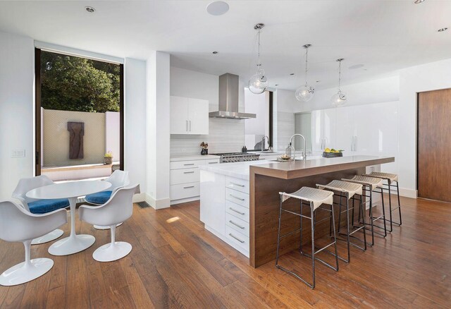 356 Woodley Rd, Montecito, CA 93108 - kitchen featuring wall chimney range hood, modern cabinets, a large island with sink, white cabinets, and dark wood-type flooring
