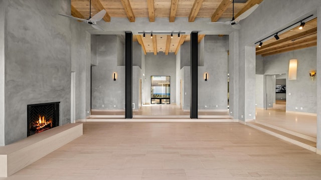 892 Toro Canyon Rd, Montecito, CA 93108 - unfurnished living room featuring a large fireplace, a wood ceiling with exposed beams, rail lighting, and a towering ceiling