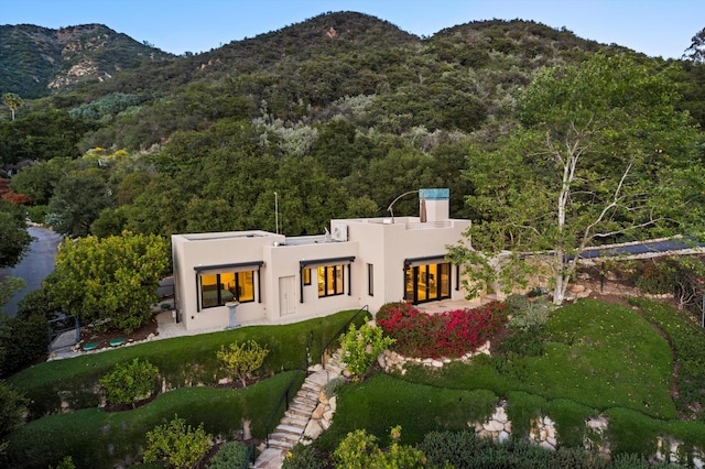 892 Toro Canyon Rd, Montecito, CA 93108 - back of house featuring stucco siding, a mountain view, a wooded view, a chimney, and a yard