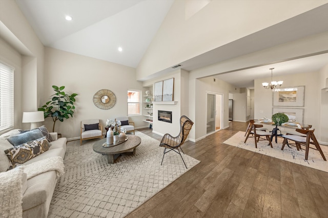 7134 Phelps Rd, Goleta, CA 93117 - living room featuring a glass covered fireplace, a chandelier, hardwood / wood-style flooring, high vaulted ceiling, and baseboards
