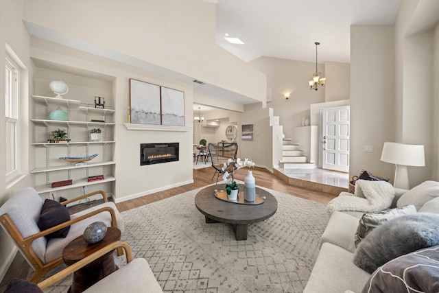 7134 Phelps Rd, Goleta, CA 93117 - living room with a chandelier, wood finished floors, baseboards, a glass covered fireplace, and high vaulted ceiling