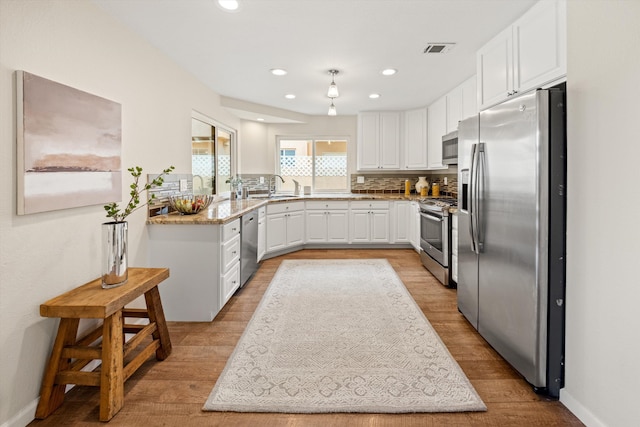 7134 Phelps Rd, Goleta, CA 93117 - kitchen with appliances with stainless steel finishes, a sink, white cabinets, light wood-style flooring, and recessed lighting