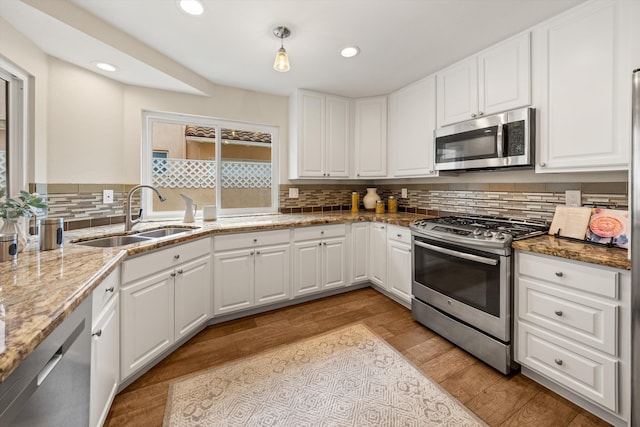 7134 Phelps Rd, Goleta, CA 93117 - kitchen with appliances with stainless steel finishes, a sink, decorative backsplash, light wood-type flooring, and white cabinetry