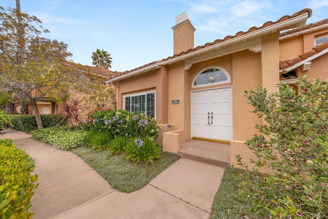 7134 Phelps Rd, Goleta, CA 93117 - doorway to property with a chimney, stucco siding, and a tile roof