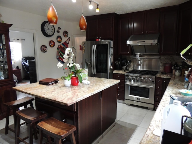 1307 San Andres St, Santa Barbara, CA 93101 - kitchen with under cabinet range hood, appliances with stainless steel finishes, a kitchen island, light tile patterned flooring, and light stone counters