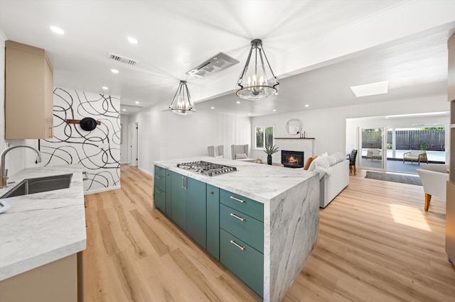 1570 Mountain View Dr, Solvang, CA 93463 - kitchen featuring a sink, stainless steel gas stovetop, light wood-type flooring, a glass covered fireplace, and green cabinetry