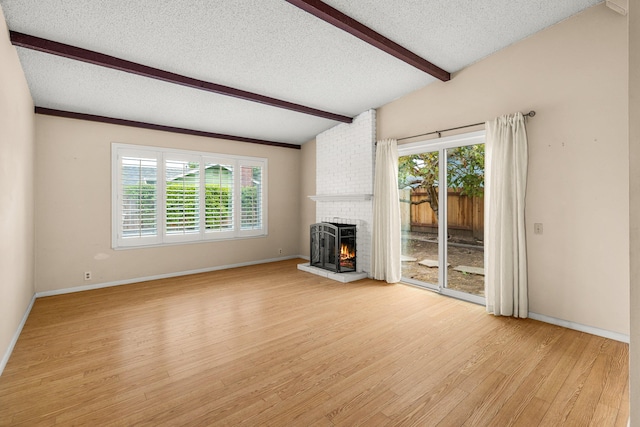 4595 Aragon Dr, Carpinteria, CA 93013 - unfurnished living room featuring light wood-style floors, a textured ceiling, plenty of natural light, and a brick fireplace