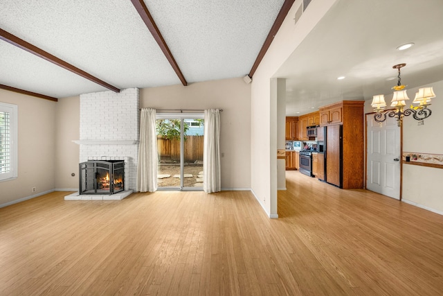 4595 Aragon Dr, Carpinteria, CA 93013 - unfurnished living room with a chandelier, a fireplace, light wood finished floors, beamed ceiling, and a textured ceiling