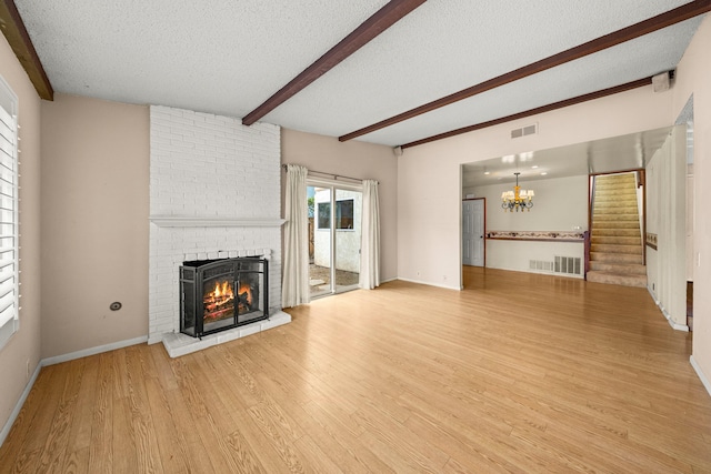 4595 Aragon Dr, Carpinteria, CA 93013 - unfurnished living room with a brick fireplace, a textured ceiling, beam ceiling, light wood finished floors, and a chandelier