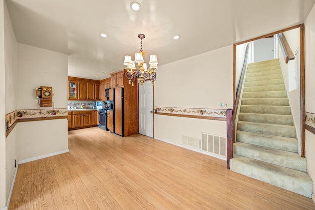 4595 Aragon Dr, Carpinteria, CA 93013 - kitchen with a chandelier, stainless steel range with gas stovetop, brown cabinets, light wood finished floors, and recessed lighting