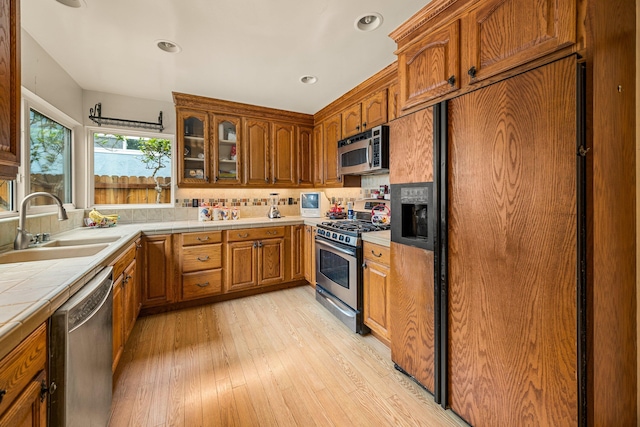 4595 Aragon Dr, Carpinteria, CA 93013 - kitchen featuring appliances with stainless steel finishes, tile countertops, tasteful backsplash, light wood-style floors, and brown cabinetry