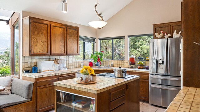 1010 Portesuello Ave, Santa Barbara, CA 93105 - kitchen with stainless steel fridge, tile countertops, tasteful backsplash, and high vaulted ceiling