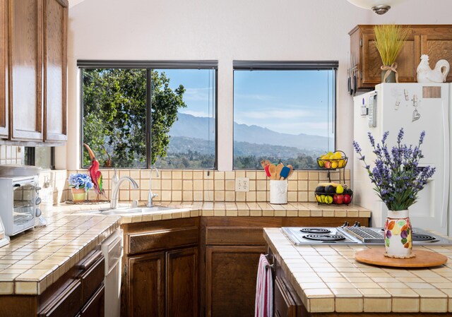 1010 Portesuello Ave, Santa Barbara, CA 93105 - kitchen with tile counters, a mountain view, a sink, stovetop with downdraft, and backsplash