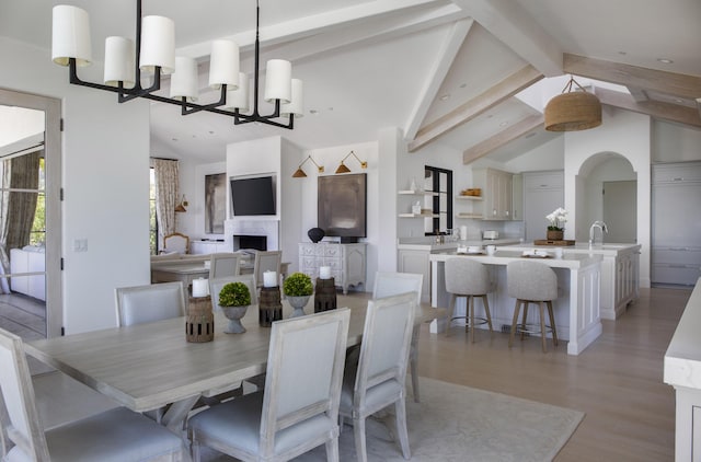 2720 Montecito Ranch Pl, Summerland, CA 93067 - dining space featuring a chandelier, light wood-type flooring, a fireplace, and arched walkways