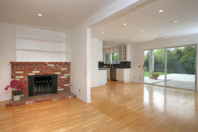 6231 Covington Way, Goleta, CA 93117 - unfurnished living room featuring light wood-type flooring, recessed lighting, a brick fireplace, a sink, and baseboards