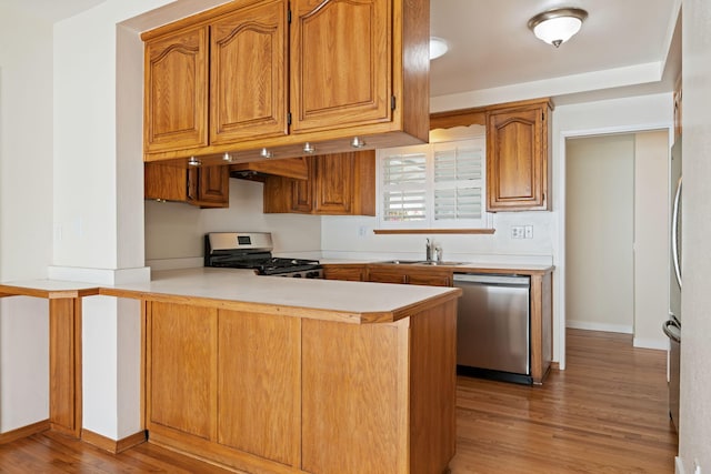 7659 Dartmoor Ave, Goleta, CA 93117 - kitchen featuring appliances with stainless steel finishes, a peninsula, light wood-style flooring, light countertops, and brown cabinetry
