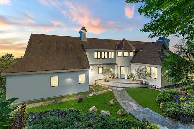 1157 Glenview Rd, Montecito, CA 93108 - back of property at dusk featuring a chimney, a shingled roof, a lawn, and stucco siding