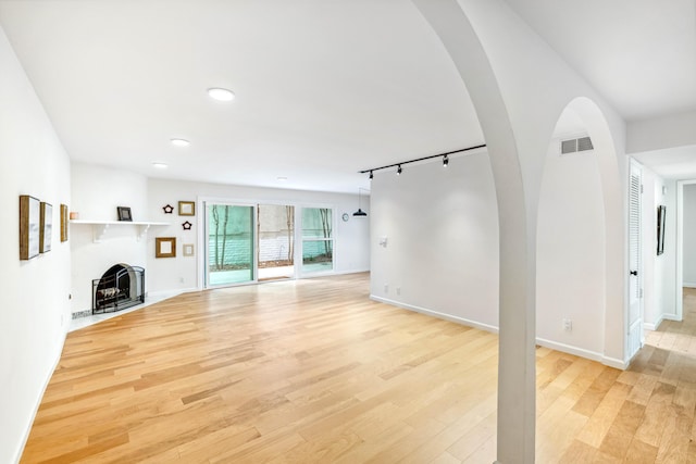 2624 State St # 1, Santa Barbara, CA 93105 - unfurnished living room featuring light wood-type flooring, rail lighting, recessed lighting, a fireplace with flush hearth, and arched walkways