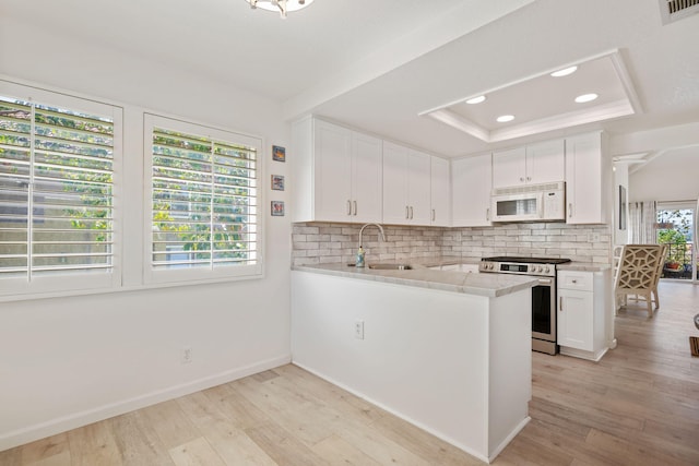 5965 Paseo Encantada, Camarillo, CA 93012 - kitchen with stainless steel range, white microwave, a tray ceiling, a sink, and tasteful backsplash