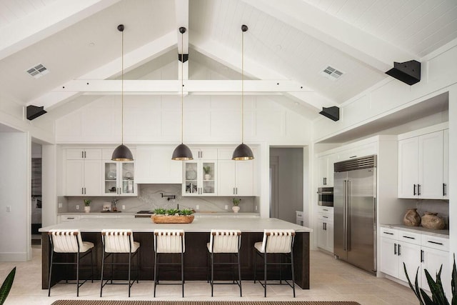120 Polo Way, Carpinteria, CA 93013 - kitchen with stainless steel appliances, high vaulted ceiling, decorative backsplash, white cabinetry, and a kitchen breakfast bar