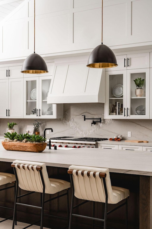 120 Polo Way, Carpinteria, CA 93013 - kitchen with white cabinetry, tasteful backsplash, hanging light fixtures, a breakfast bar, and glass insert cabinets