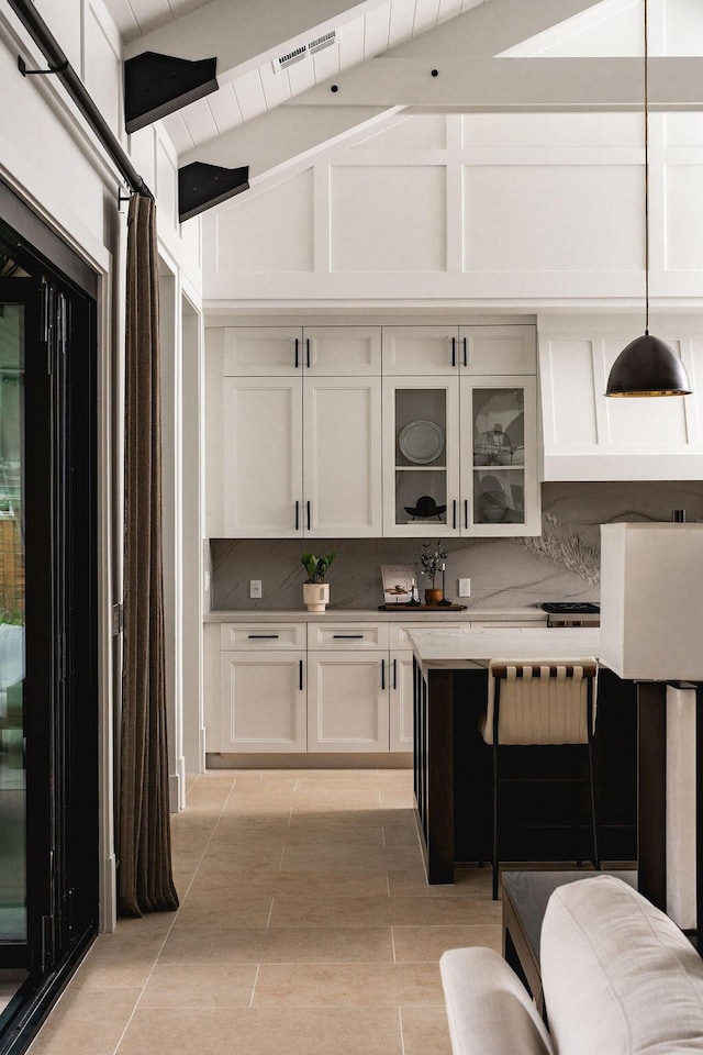 120 Polo Way, Carpinteria, CA 93013 - kitchen featuring backsplash, white cabinetry, glass insert cabinets, vaulted ceiling, and hanging light fixtures