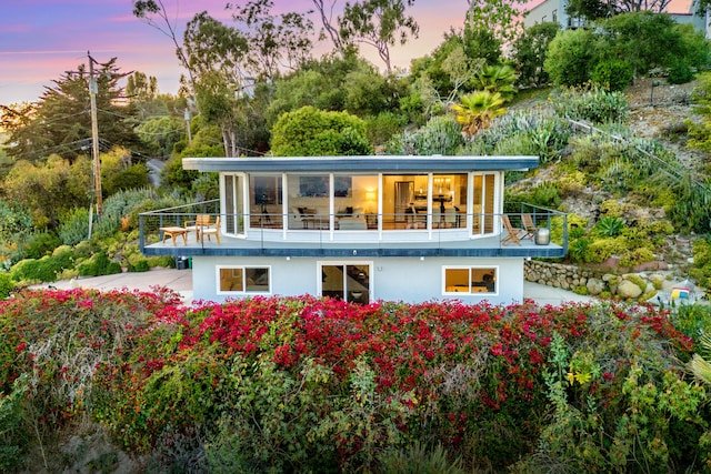 128 Las Alturas Rd, Santa Barbara, CA 93103 - back of property at dusk featuring a balcony and stucco siding