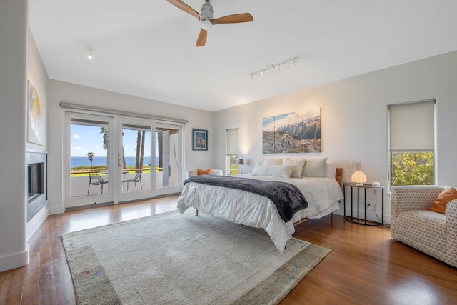 1312 Shoreline Dr, Santa Barbara, CA 93109 - bedroom featuring access to exterior, wood finished floors, rail lighting, a glass covered fireplace, and ceiling fan