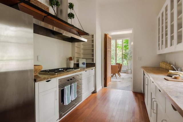 405 Toro Canyon Rd, Carpinteria, CA 93013 - kitchen featuring appliances with stainless steel finishes, hardwood / wood-style floors, white cabinets, glass insert cabinets, and light stone counters