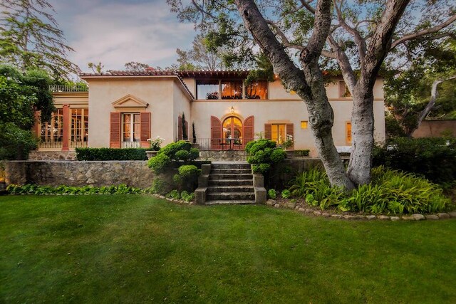 405 Toro Canyon Rd, Carpinteria, CA 93013 - view of front facade with french doors, a front yard, stucco siding, and stairs