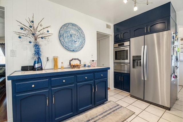 412 Milky Way, Lompoc, CA 93436 - kitchen with appliances with stainless steel finishes, a warming drawer, blue cabinetry, light tile patterned flooring, and light countertops