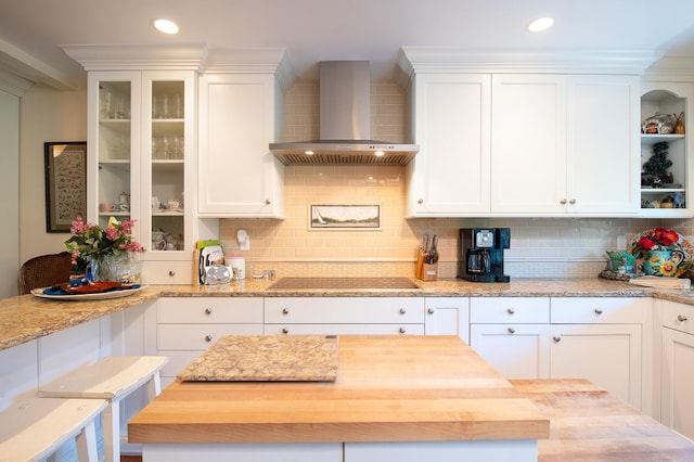 23 La Cumbre Cir, Santa Barbara, CA 93105 - kitchen featuring wall chimney exhaust hood, black electric stovetop, white cabinetry, wooden counters, and tasteful backsplash