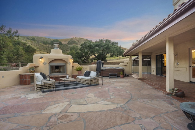 80 Bobcat Springs Rd, Buellton, CA 93427 - patio terrace at dusk with an outdoor fireplace, a hot tub, and a patio area