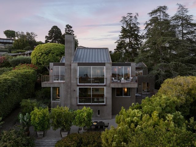 1944 Eucalyptus Hill Rd, Santa Barbara, CA 93108 - back of house with a balcony, a standing seam roof, a chimney, a metal roof, and stucco siding